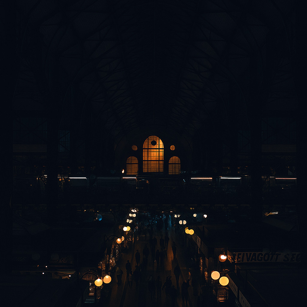 Interior of the Great Market Hall in Budapest, showcasing its grand iron structure and high vaulted roof illuminated by warm light